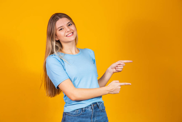 young caucasian woman smiling pointing to the side with free space for text. - Φωτογραφία, εικόνα
