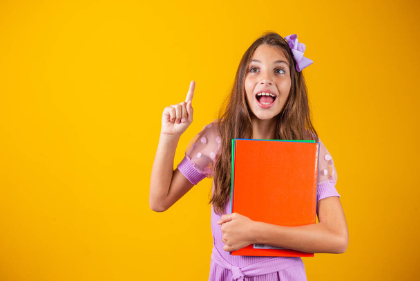 Caucasian student girl with books in her hands and her finger up. back to school - Photo, image