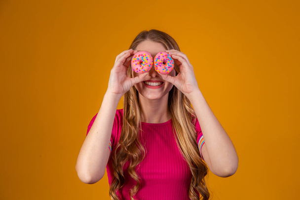 young blonde with donuts on yellow background. - Fotó, kép