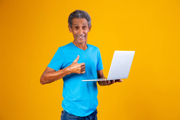 elderly man with laptop shopping or working online. Older man with his thumb up holding a notebook computer. - Foto, immagini