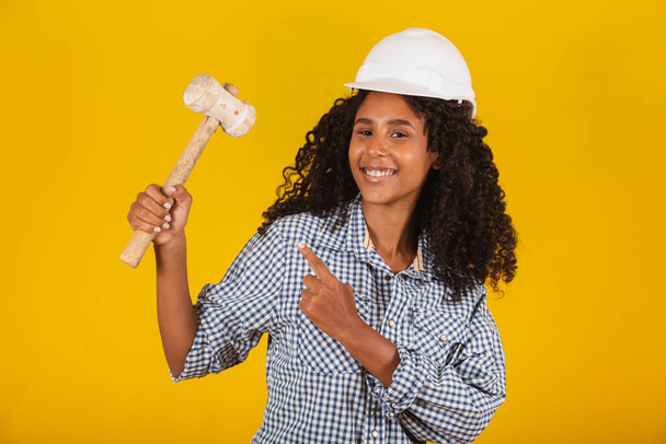 Afro female engineer holding a sledgehammer pointing - Photo, Image
