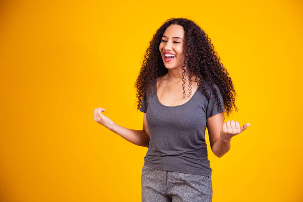 Portrait of happy beautiful young afro woman with perfect smile raised her hands up and celebrate achievement goal. - 写真・画像