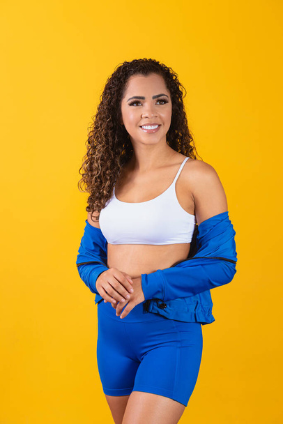 Beautiful young afro woman in fitness outfit smiling looking at camera with space for text. Vertical - Foto, Imagen