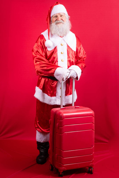 Santa Claus with his suitcase. New Year's travel concept. Santa Claus at the airport. - Foto, afbeelding
