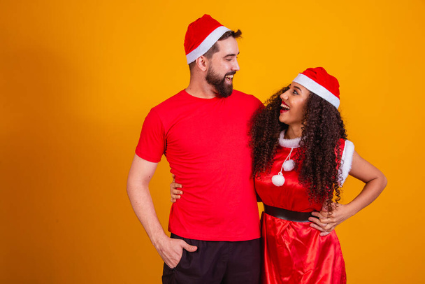 Young valentine couple dressed for Christmas night on yellow background with space for text. - Zdjęcie, obraz