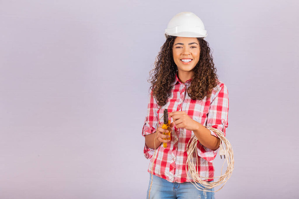 Female technique. Electrician woman on white background with space for text. Woman electrician holding wire and pliers. - Foto, immagini