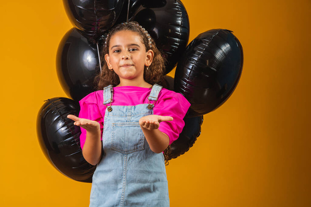 smiling little girl with black balloons on black friday. low price festival - Foto, imagen