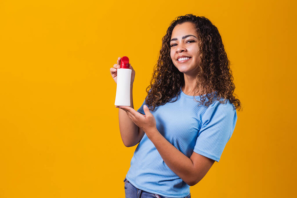 woman holding a cream in yellow background - Photo, Image
