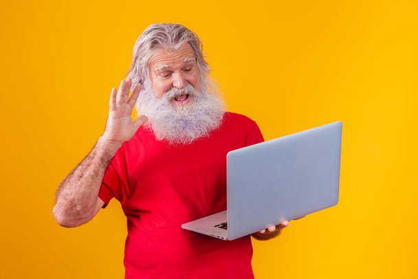 old man on yellow background making a video call on the laptop. - Фото, зображення