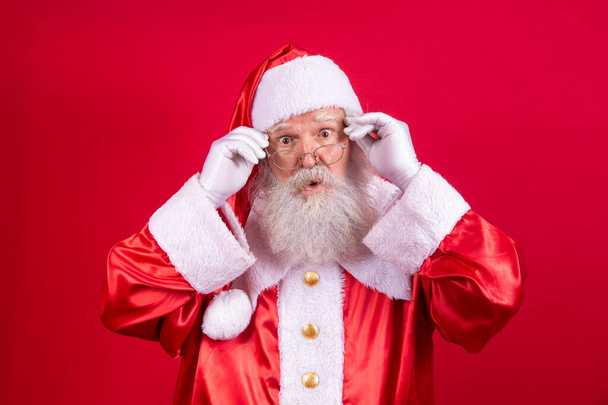 Santa Claus looking at the camera. Christmas is coming. Merry Christmas. Santa is watching. Holding his glasses. - Photo, Image