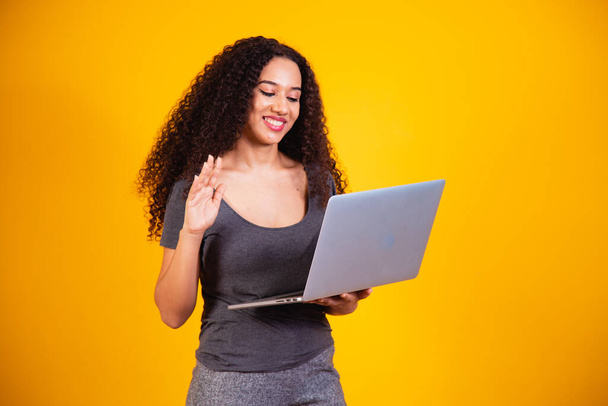 Remote! Portrait of excited young afro woman holding laptop computer on a video call. - 写真・画像