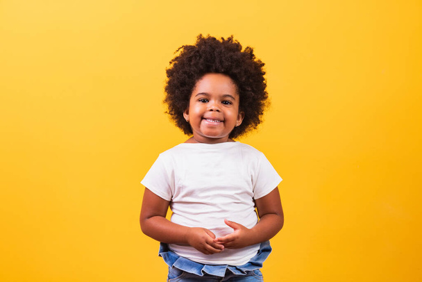 childhood and people concept - happy little african american girl on yellow background. Little black girl with black power hair smiling. - Photo, image