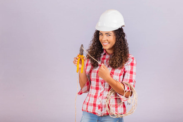 Female technique. Electrician woman on white background with space for text. Woman electrician holding wire and pliers. - Foto, Imagem