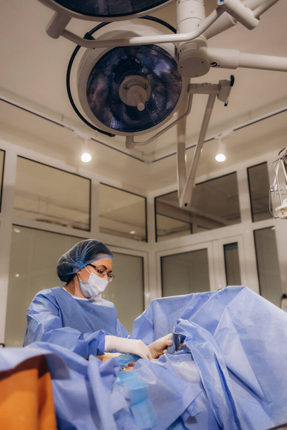 Cirujana profesional proctóloga que realiza la operación utilizando dispositivos especiales para la colonoscopia en el quirófano del hospital. Concepto quirúrgico urgente - Foto, imagen