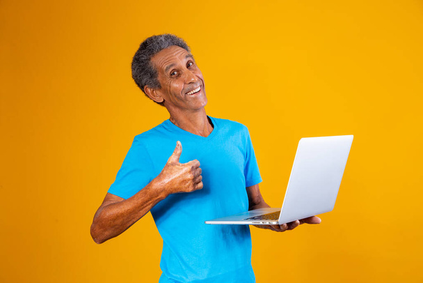 elderly man with laptop shopping or working online. Older man with his thumb up holding a notebook computer. - Photo, image