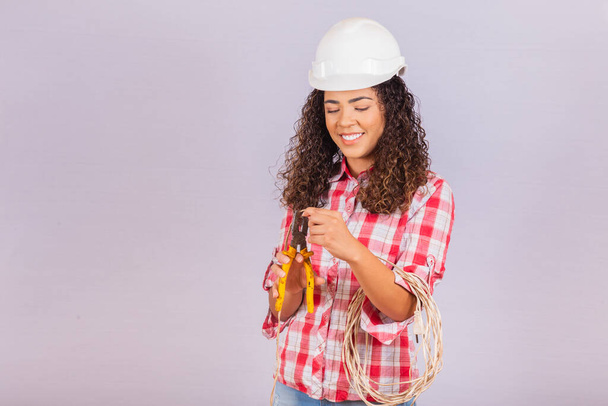 Female technique. Electrician woman on white background with space for text. Woman electrician holding wire and pliers. - Valokuva, kuva