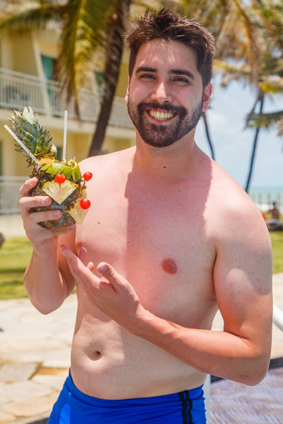 man on vacation in risort drinking sweet pineapple drink. - Foto, afbeelding
