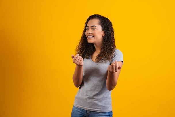 happy african woman in gray t-shirt pose on yellow background smiling - Foto, immagini
