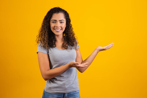 Afro woman pointing in yellow background with space for the text - Fotó, kép