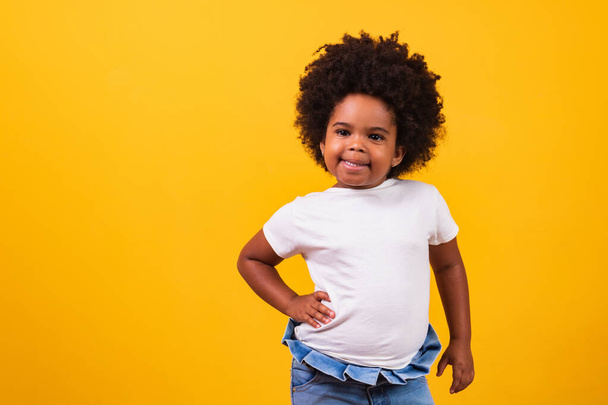 conceito de infância e pessoas - menina americana africana feliz em fundo amarelo. Pequena menina negra com poder preto cabelo sorrindo. - Foto, Imagem