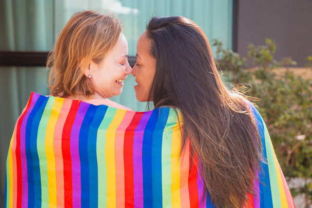 Lesbian couple with lgbt flag back to camera kissing eskimo. Valentines day - Foto, Imagem