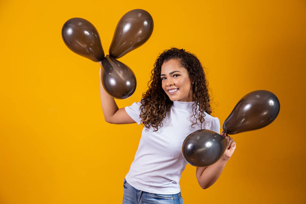 Afro woman with black balloons celebrating birthday offers. Black Friday sales - Фото, изображение
