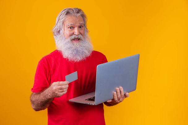 Uomo anziano con computer portatile e carta di credito bancaria. Transazione di shopping online. Metodo cashless bancario mobile. - Foto, immagini