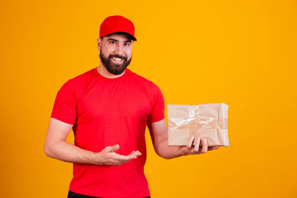 Best Service Concept. Smiling caucasian delivery man in red cap and stacking holding stack of cardboard boxes while standing isolated over yellow studio background. Mail carrying packages - Φωτογραφία, εικόνα