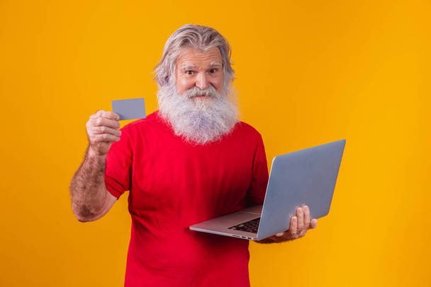Elderly man holding laptop computer and bank credit card. Online shopping transaction. Mobile banking cashless method. - Fotoğraf, Görsel