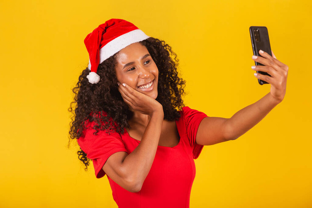 Afro young man in Christmas hat making video call on yellow background. - Foto, immagini