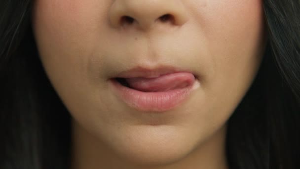 Młoda kobieta gryzie seksowne usta i liże językiem. Atrakcyjne młode dziewczyny usta i usta, zdrowy makijaż twarzy. zbliżenie zmysłowe kobieta lizanie pulchne usta w zwolnionym tempie uśmiech 4K - Materiał filmowy, wideo