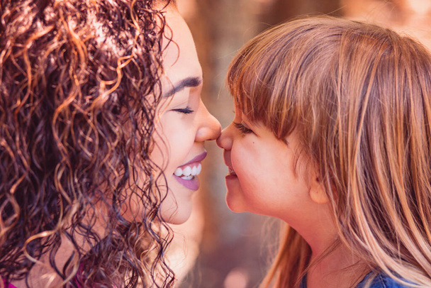 mother and daughter giving Eskimo kiss. Mothers Day. Afro mother and white daughter - Foto, imagen