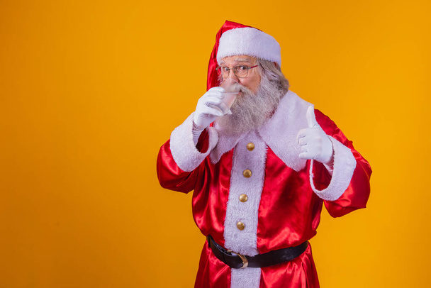 Санта-Клаус с водой на желтом фоне. - Фото, изображение