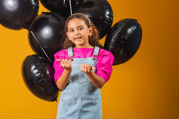 smiling little girl with black balloons on black friday. low price festival - Фото, изображение