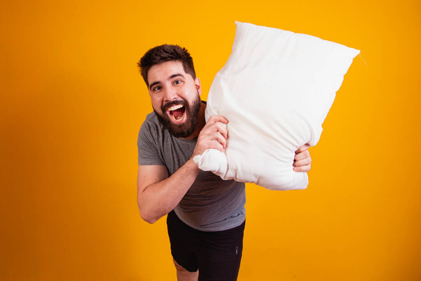fun and playful boy with a pillow in his hand playing pillow war for the camera. - Fotó, kép