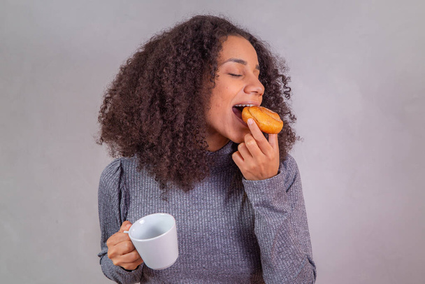afro woman eating donuts and drinking coffee - Foto, Bild