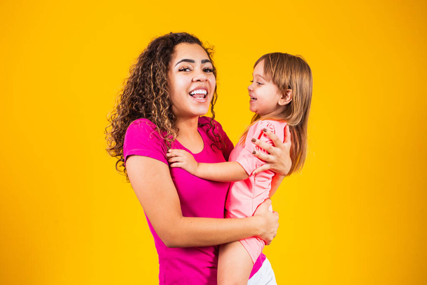 Joyeuse fête des mères ! Adorable enfant caucasien avec sa mère sur fond jaune. - Photo, image