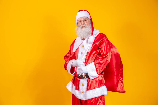Real Santa Claus with a red background, wearing glasses, gloves and a hat looking side. - Zdjęcie, obraz