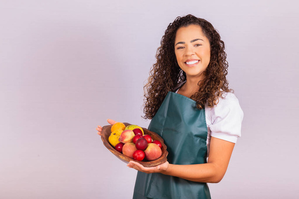joven campesina sosteniendo un tazón con frutas. Mango, Melocotón y manzana en la canasta en la mano de la niña - Foto, imagen