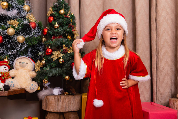 Cute little caucasian girl dressed for christmas at home. Girl on Christmas background dressed in noelete - Foto, afbeelding