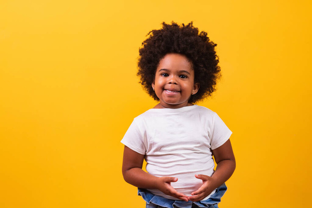 childhood and people concept - happy little african american girl on yellow background. Little black girl with black power hair smiling. - Фото, зображення