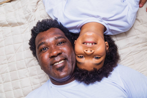 afro father and son lying in bed - Фото, изображение