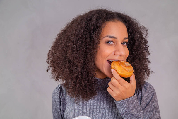 afro woman eating donuts and drinking coffee - Φωτογραφία, εικόνα