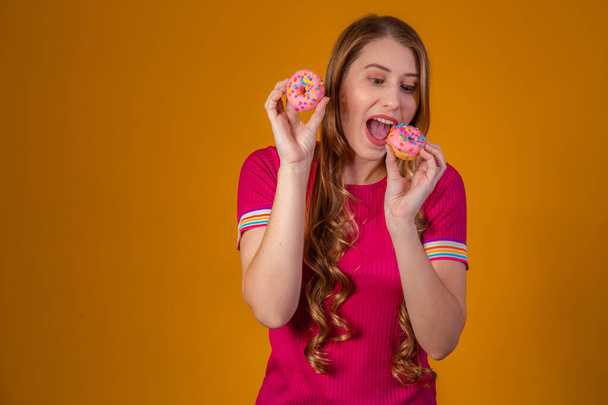 young blonde with donuts on yellow background. - Foto, Imagem