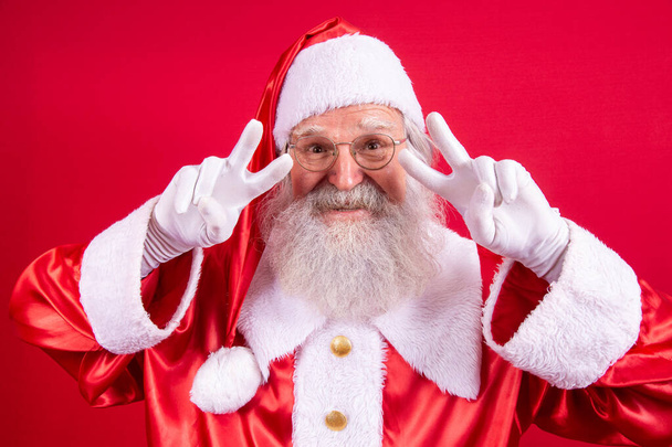 Santa Claus looking at the camera. Christmas is coming. Merry Christmas. Peace. V sign. - Foto, afbeelding