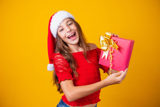 Excited little Caucasian girl with open mouth holding a Christmas present. - 写真・画像