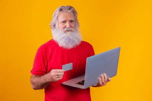 Starszy mężczyzna z laptopem i kartą kredytową. Transakcja zakupów online. Metoda bankowości mobilnej bezgotówkowa. - Zdjęcie, obraz