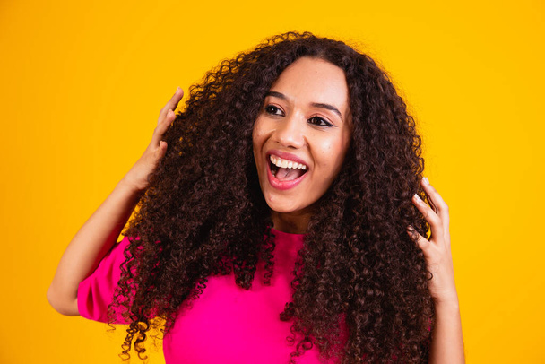 Beauty portrait of african american woman with afro hairstyle and glamour makeup. Brazilian woman. Mixed race. Curly hair. Hair style. Yellow background - Zdjęcie, obraz