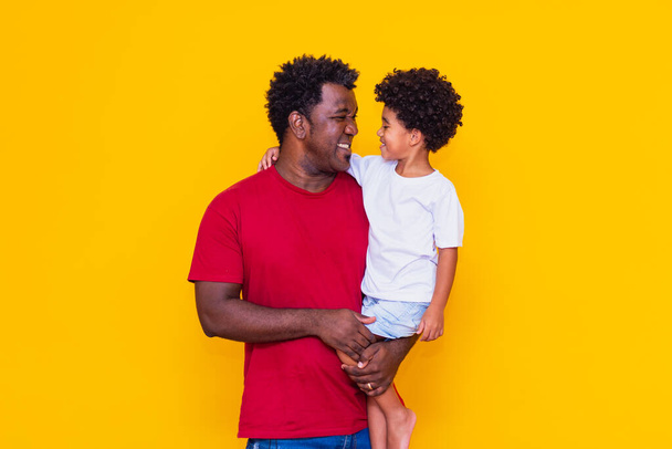 Vater und Sohn auf gelbem Hintergrund lächeln. Vatertagskonzept - Foto, Bild