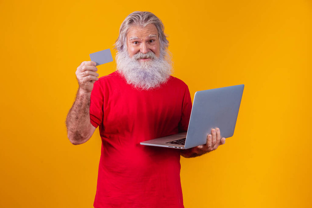 Elderly man holding laptop computer and bank credit card. Online shopping transaction. Mobile banking cashless method. - Zdjęcie, obraz